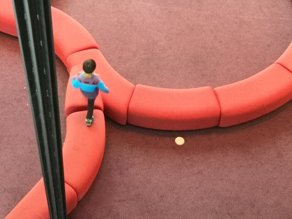 A small child running across the curved red bench seats of the the Great Hall of the National Gallery of Victoria